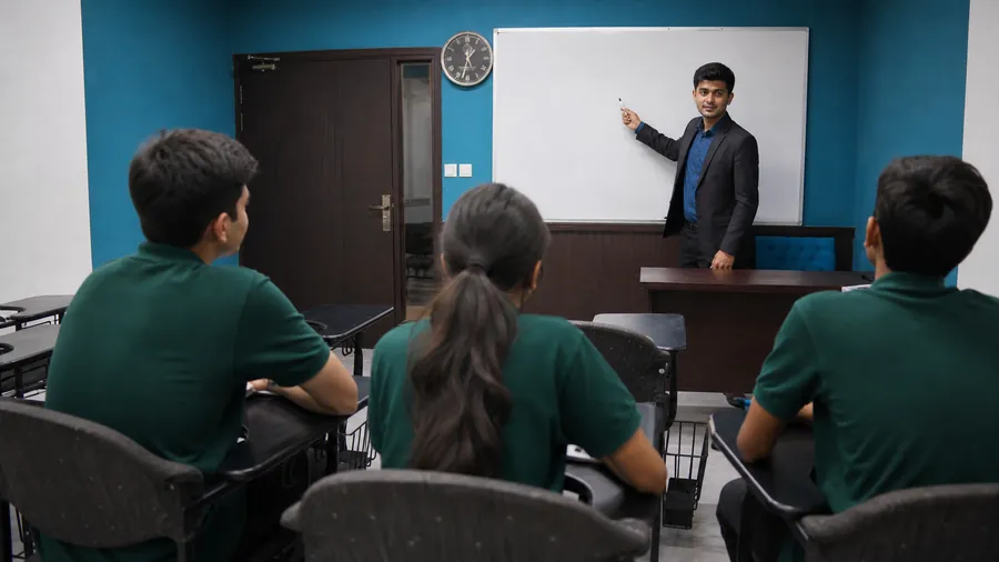 A teacher working through a problem at the board with students